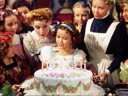 Princess blowing her birthday cake as the headmistress Ms. Minchin and other students look on.